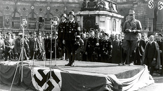 Heinrich Himmler standing on a podium holding a speech